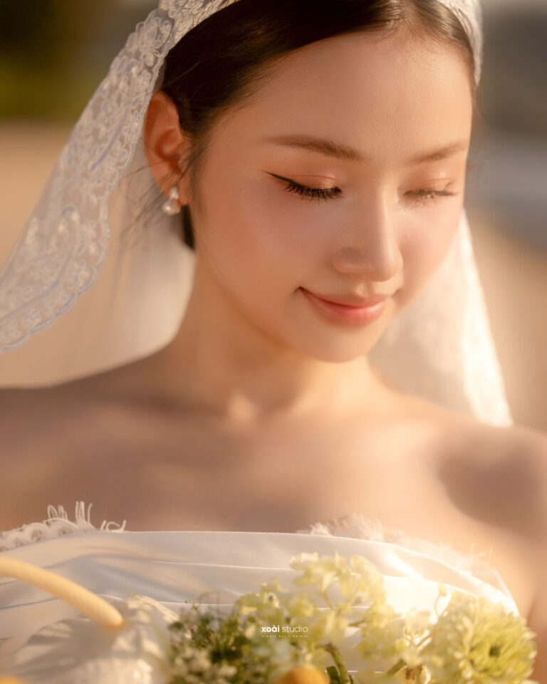 Cận cảnh cô dâu Hà nhìn xuống bó hoa trong nắng bình minh.